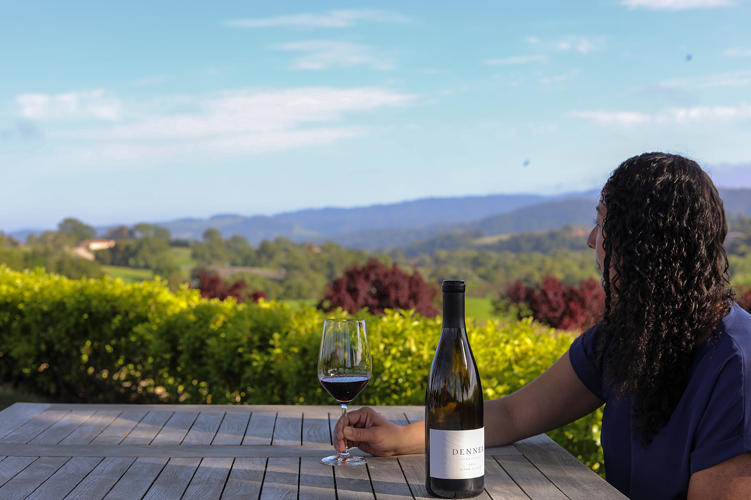 Person enjoying the view and drinking wine at Denner Vineyards.